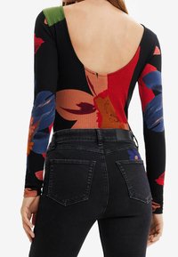 Black ribbed bodysuit with long sleeves, featuring bold floral patterns in red, blue, and green. Low back design and fitted silhouette.