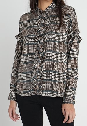 Chemise à motifs à carreaux, avec des tons de marron, crème et bleu. Présente des manches à volants et une rangée de boutons sur le devant.