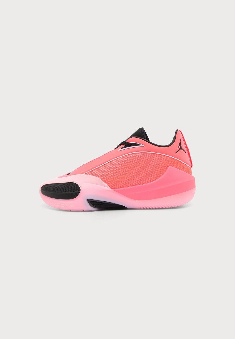 Chaussure de sport basse rose et noire avec une tige en mesh, une semelle épaisse et le logo Jumpman sur le côté du talon sur un fond uni.
