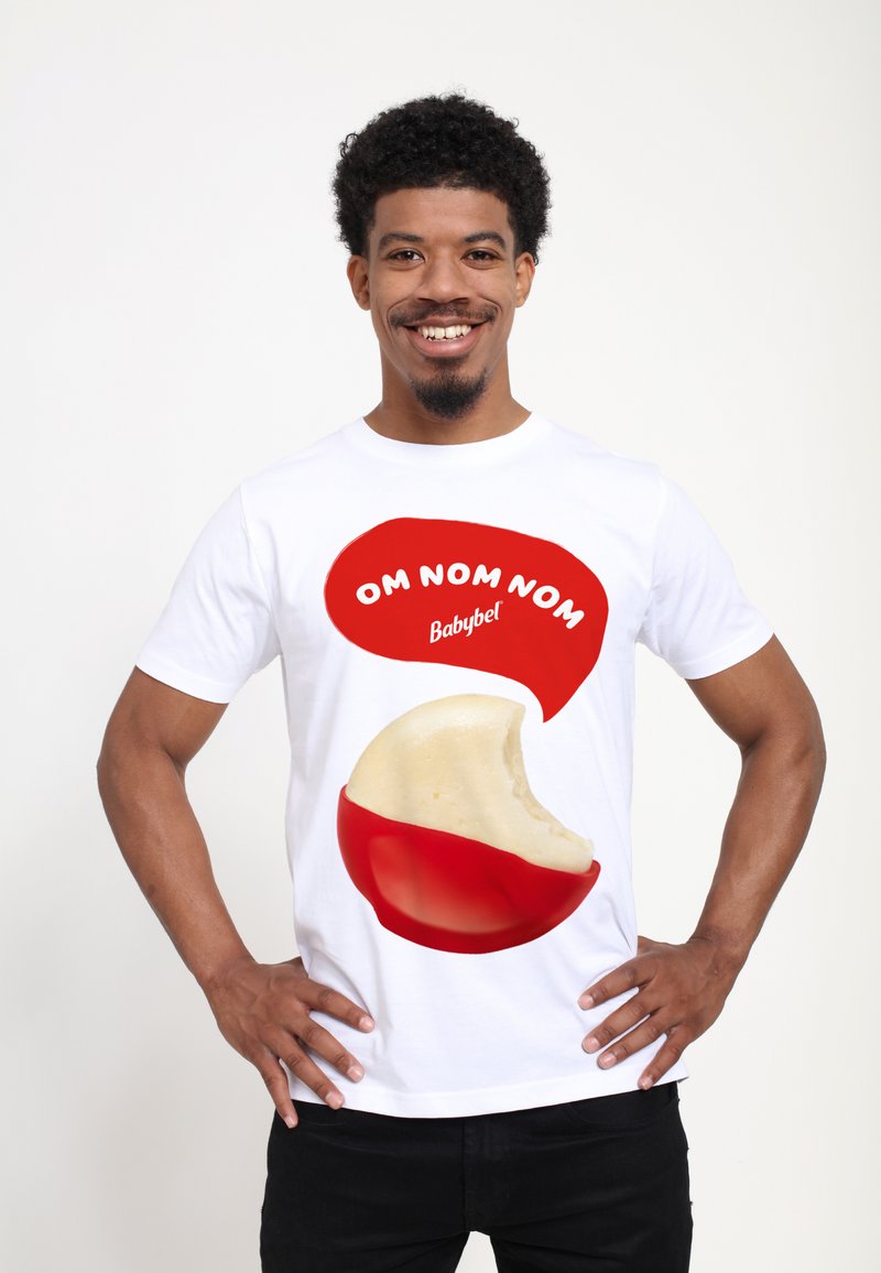 Vit t-shirt med en grafik av ett delvis uppätet Babybel-osthjul, med en röd pratbubbla som säger "OM NOM NOM."
