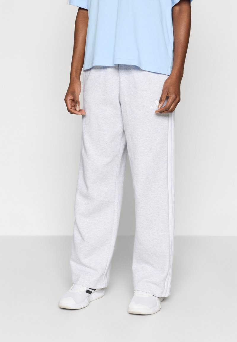 Világosszürke melegítőnadrág puha anyagból, laza szabással, oldalsávokkal és rugalmas derékrésszel. Fehér tornacipővel párosítva.