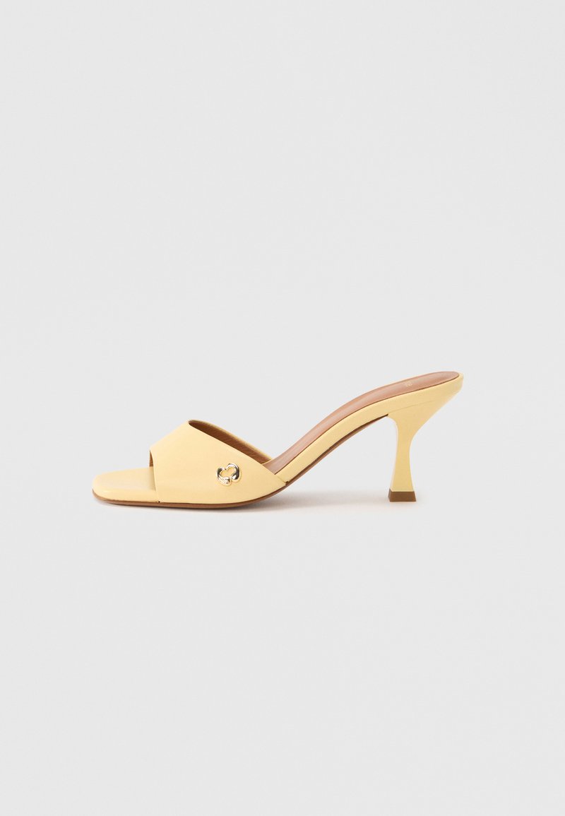 Sandale à talon ouverte jaune avec une large bride et un détail argenté. Matériau lisse, silhouette élégante, et talon bloc solide.