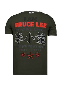 Olivengroen T-shirt met korte mouwen en kleurrijke tekst met de woorden "I AM BRUCE LEE" en drie rode sterontwerpen langs de onderkant.