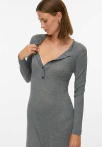 Siva rebrasta obleka z dolgimi rokavi in globokim V-izrezom ter gumbnimi detajli na ovratniku. Mehka tkanina z oprijetim krojem.