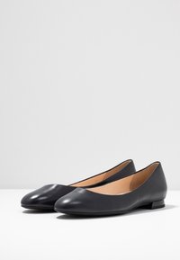 Black leather ballet flats with a rounded toe, low heel, and smooth texture. Features a simple design and neutral color for versatility.