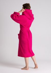 Accappatoio in terry cloth fucsia con cappuccio, dotato di maniche lunghe, cintura in vita e tasche laterali, mostrato di spalle.