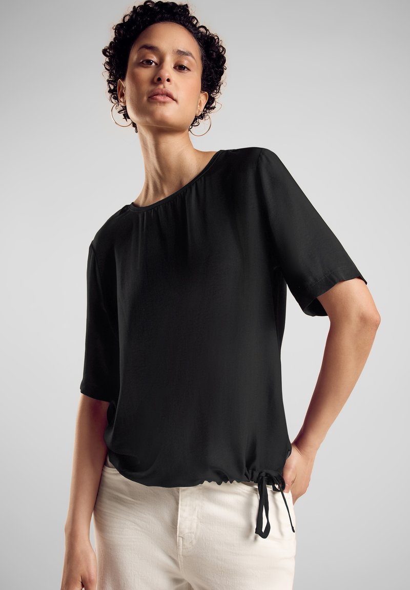 Schwarzes kurzes T-Shirt mit Rundhalsausschnitt und gerafftem Kordelzugsaum. Hergestellt aus glattem Stoff, mit lockerer Passform und mühelosem Fall.