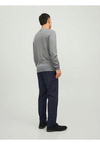 Maglione grigio con maniche lunghe, polsini e orlo a coste. Abbinato a pantaloni blu navy, con un leggero motivo a quadri e una vestibilità classica.
