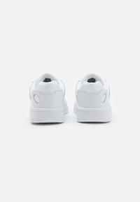 Zapatillas de cuero blanco con punta redonda, cuello acolchado y pestaña en el talón texturizada. "TOMMY JEANS" grabado en el talón.