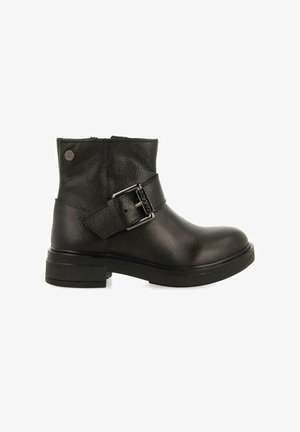 Stivaletto nero in pelle con finitura lucida, forma arcuata, dettaglio con fibbia laterale e suola bassa in gomma nera.