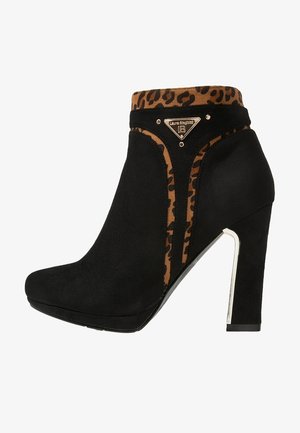 Stivaletto alla caviglia in camoscio nero con tacco alto, rifinito con stampa leopardata e logo triangolare dorato del marchio sul lato vicino alla parte superiore.