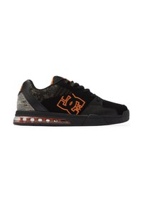 Zapatilla negra con acentos naranjas; hecha de ante y malla. Cuenta con un cuello acolchado, suela gruesa con amortiguación de aire y detalles del logo.