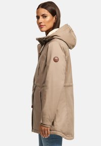 Beige Kapuzenjacke mit Fleece-Futter, Reißverschlüssen und einem Logoflicken am linken Ärmel. Verfügt über eine verstellbare Kordel und Seitentaschen.