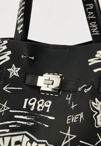 Fekete bőrtáska fehér graffiti stílusú nyomattal, ezüst fém kapoccsal és fekete bőr fogantyúkkal.