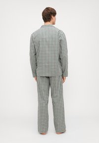 Conjunto de pijama a cuadros verdes y blancos que incluye una camiseta de botones de manga larga y pantalones sueltos a juego con una textura suave.
