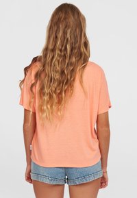 Kurzärmliges, pfirsichfarbenes T-Shirt aus leichtem Stoff. Verfügt über eine lockere Passform, runden Halsausschnitt und ein leicht abfallendes Schulterdesign mit subtiler Textur.