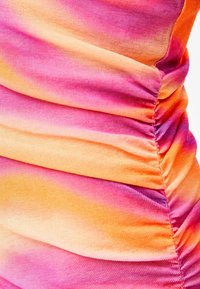 Nařasená látka v růžové, oranžové a žluté barvě s degradací; měkká textura s hladkým povrchem; obsahuje horizontální detail shromáždění a jemný lesk.