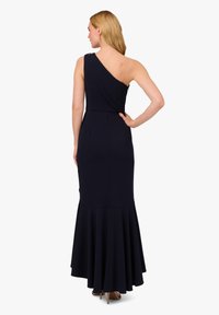 Ein schulterfreies Kleid in Marineblau aus glattem Stoff, mit einem weit schwingenden Saum und subtilen Details an der Schulter. Schlichte und elegante Silhouette.