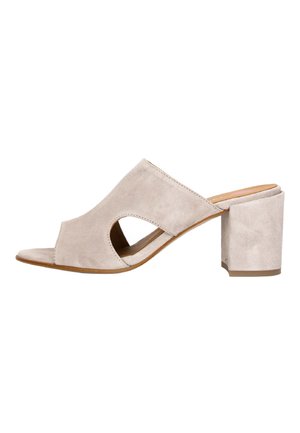Beige ruskindsandal med blokhæl, åben tå og udskæringer i siden, med en tekstureret overflade og en bred rem over foden.