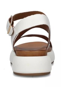 Sandali bianchi in pelle con soletta marrone, caratterizzati da ampie cinghie incrociate e un accento in oro sulla fibbia. Il design con tacco a blocco offre stabilità.
