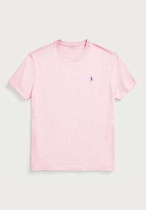 Lys rosa t-skjorte med korte ermer laget av bomull, med rund halslinning og en liten blå brodert logo på venstre bryst.