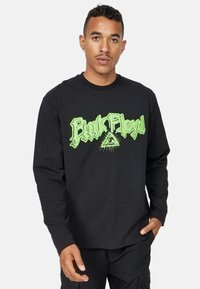 Sort langærmet t-shirt med stor, lys grøn "Pink Floyd" tekst og et øje-symbol, lavet af blødt bomuldsstof.