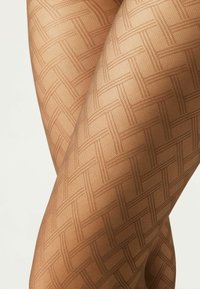 Collants avec un motif géométrique dans une couleur beige chaud, présentant un design de trame texturée qui crée un effet de treillis visuel.