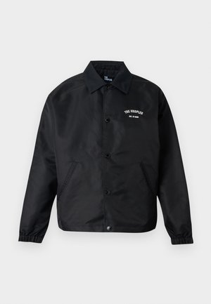 Čierna coach bunda na zapínanie s dlhými rukávmi, elastickými manžetami, bočnými vreckami a bielym nápisom "THE KOOPLES EST. IN 2008" na hrudi.