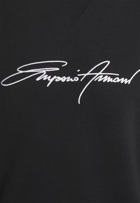 Svart sweatshirt med v-ringad design och en framträdande vit broderad logotyp som läser "Superior Armand". Slät tygtextur.