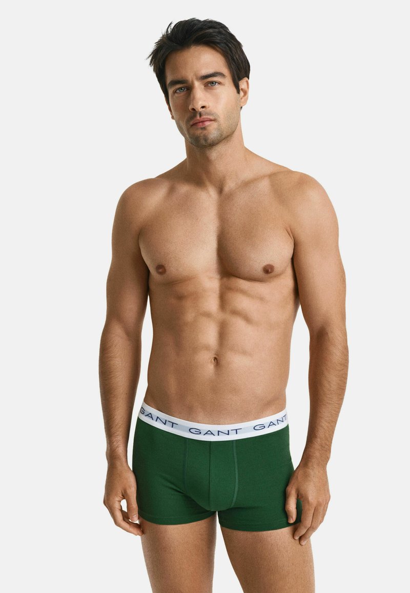 Boxer briefs in cotone verde con vita bianca su cui è stampato il nome del marchio "GANT" in blu. Il design è aderente e di tessuto liscio.