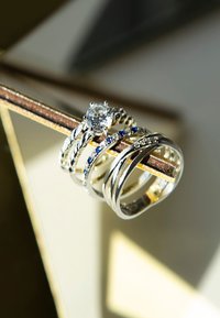 Set van zilveren ringen met een centrale solitaire diamant, gedraaide band en accentstenen in blauw en helder met gepolijste afwerkingen.