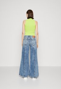 Neon green sleeveless top paired with wide-leg, light blue denim jeans, featuring a high waist and back pocket detailing.
