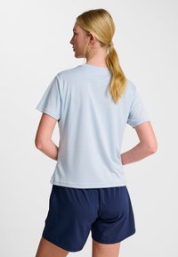 T-shirt de sport à manches courtes bleu clair avec un col ras du cou et un tissu lisse, associé à un short bleu marine. Vue arrière montrant les détails du design.