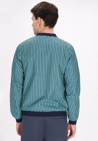 Herenjas in donkerblauw en turkoois houndstooth patroon, met ribgebreide kraag en manchetten, voorzien van elastische tailleband en een soepele textuur.
