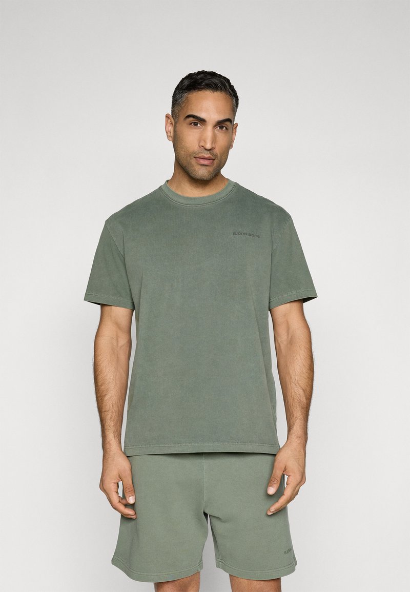 Grøn bomulds t-shirt med korte ærmer og rund hals, med et subtilt logo på venstre bryst. Blød tekstur, parret med matchende shorts.