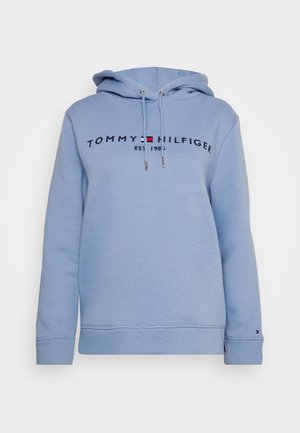 Sweat à capuche bleu clair avec cordon de serrage, arborant un logo imprimé en noir et rouge sur la poitrine. Texture douce, semblable au coton.