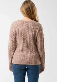 Sweter w warkocze w jasnym beżowym kolorze z prążkowanym dołem i mankietami, z teksturowanym wzorem i luźnym krojem.