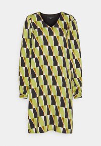 Robe à manches longues avec col en V présentant un motif géométrique composé de formes noires, vert olive, blanches et orange sur un fond clair.