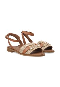 Braune Ledersandalen mit gewebtem Strohdetail, flacher Sohle, verstellbarem Knöchelriemen und metallischen Akzenten an der Vorderseite.