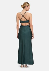 Smaragdgrünes Satin-Kleid mit figurbetontem Schnitt, gekreuzten Rückenträgern und Pünktchenmuster; verfügt über einen Reißverschluss hinten.