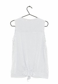 Blouse sans manches en tissu blanc avec un motif à pois noir. Elle présente un ourlet fin et un détail noué froncé en bas.