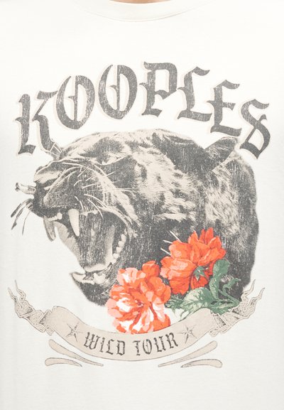 Βρυχώμενη μαύρη πάνθηρα με πορτοκαλί λουλούδια και τις λέξεις "KOOPLES" πάνω και "WILD TOUR" κάτω σε λευκό φόντο.