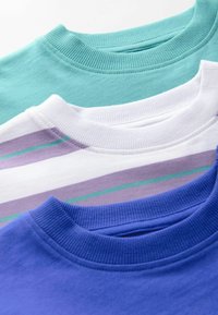 Tres camisetas de cuello redondo expuestas: una en color teal sólido, una blanca con rayas en lavanda y teal, y una en color púrpura sólido. Tejido de algodón, cuellos con ribete.
