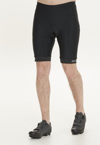 Pantalones cortos de ciclismo negros hechos de material elástico, con un asiento acolchado integrado. El diseño se ajusta al cuerpo con costuras planas y un logo.