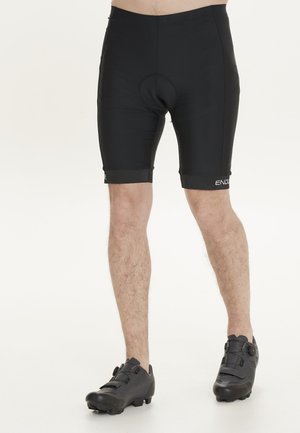 Pantalones cortos de ciclismo negros hechos de material elástico, con un asiento acolchado integrado. El diseño se ajusta al cuerpo con costuras planas y un logo.