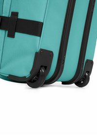 Teal koffer met zwarte hardware, voorzien van textiel, drie glijdende wielen en een veilige bevestiging met zwarte riem.