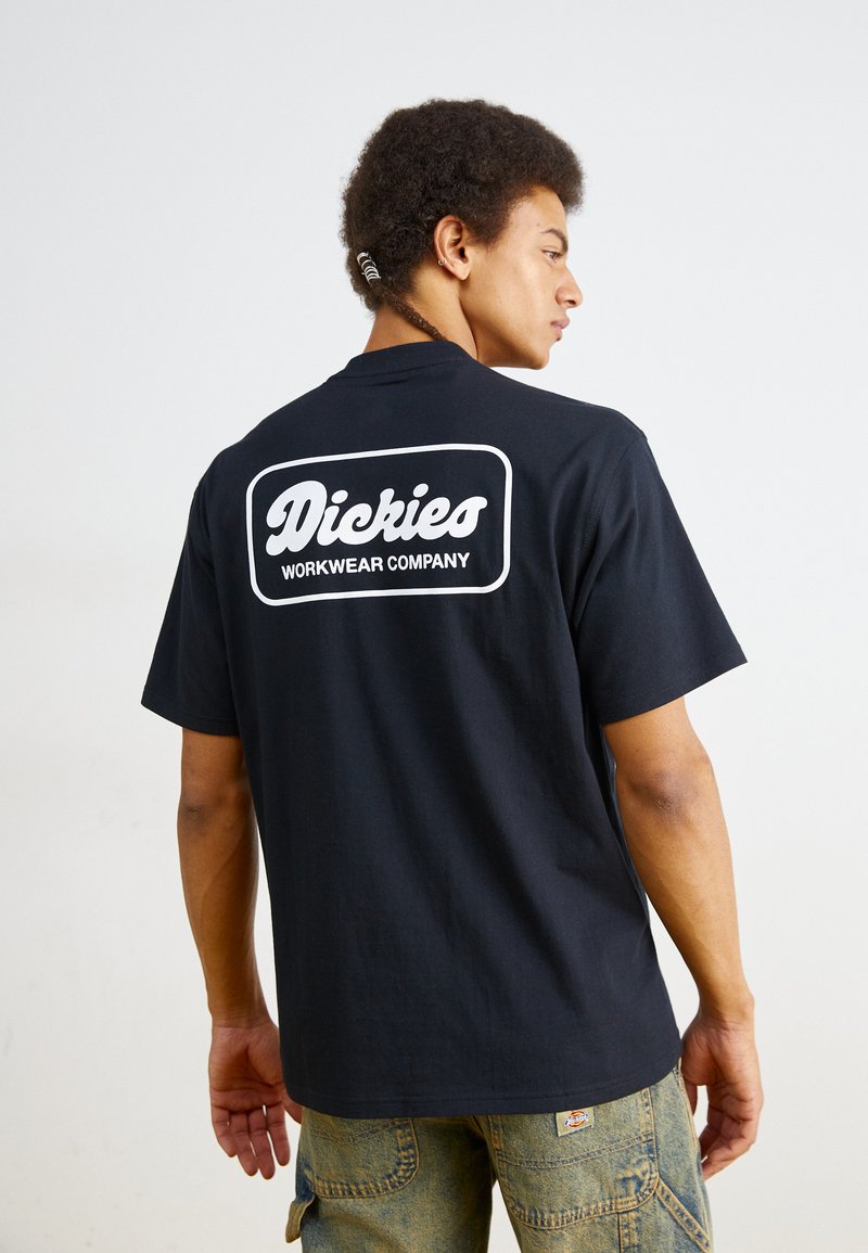 Black cotton t-shirt featuring a large white logo on the back stating "Dickies Workwear Company." Short sleeves and relaxed fit.