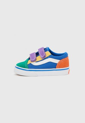 Zapatilla infantil con malla azul, puntera verde, talón naranja, detalles amarillos, franja blanca y doble cierre de velcro morado sobre suela blanca.