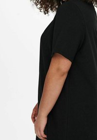 Svart oversized t-shirt i mjukt tyg, med korta ärmar och avslappnad passform. Enkelt mönster utan synliga mönster eller detaljer.