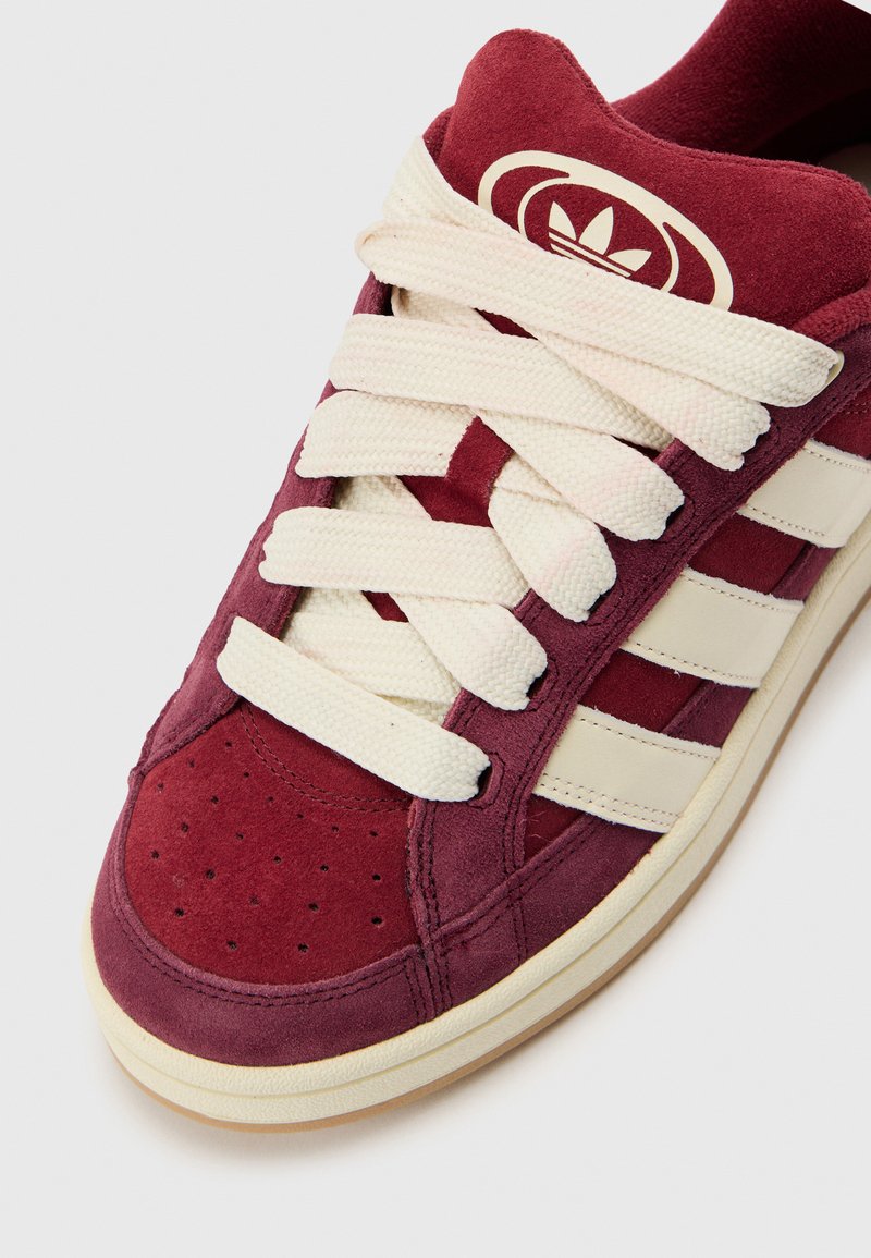 Baskets en suède bordeaux avec rayures crème, bout rond, tige texturée et lacets plats. Comprend des perforations pour la respirabilité.